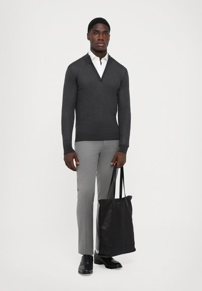 Grauer Pullover mit Reißverschluss, hellgraue maßgeschneiderte Hose, schwarze Schuhe und eine schwarze Tragetasche. Glatter Stoff, moderner Schnitt, keine Muster oder Akzente.