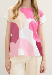 Top a maniche corte in tessuto leggero con forme astratte rosa e rosse su uno sfondo bianco. Collo rotondo, vestibilità comoda.