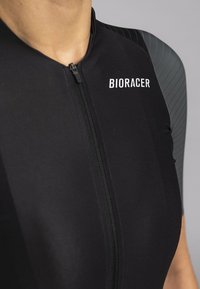 Black cycling suit with a short front zipper, featuring a textured gray shoulder design. "BIORACER" logo in white on the chest.