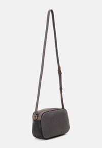 Sac en bandoulière en cuir avec une finition lisse gris foncé, détail de fermeture éclair doré et une sangle mince et réglable. Forme rectangulaire compacte.