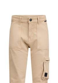 Pantaloni cargo beige in cotone con chiusura a bottone, tasche frontali e una tasca laterale con dettaglio etichetta nera. Texture liscia e vestibilità dritta.