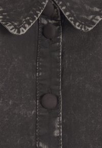 Chemise en tissu noir à finition brillante, dotée d'un col et de boutons ronds recouverts de tissu sur la patte de boutonnage avant.