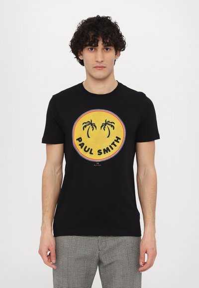 Sort T-shirt med korte ærmer, der har et cirkulært gult grafik med palmer og teksten "PAUL SMITH", fremstillet af bomuldsstof.