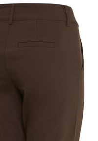 Pantalon marron sur mesure montrant la taille arrière avec passants de ceinture et une poche passepoilée simple, couture latérale partiellement visible sur fond blanc.