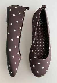 Ballerinas in Dunkelbraun mit großen weißen Punkten. Glattes Material, abgerundete Spitze und dünne schwarze Sohle. Innen mit kleineren Punkten.