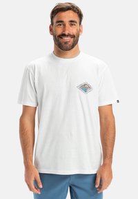 Hvid bomulds t-shirt med et diamantformet grafisk design i blå, orange og sort, med korte ærmer og rund halsudskæring.