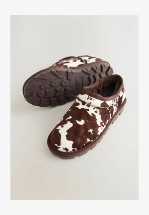 Pantofole a stampa mucca marrone e bianca realizzate in morbido pellicciotto, con una suola in gomma resistente e un design arrotondato per il massimo comfort.