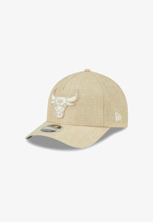 Cappellino da baseball color sabbia con un logo tridimensionale di un toro sul davanti, tessuto testurizzato e visiera curvata. Accenti bianchi sui lati.
