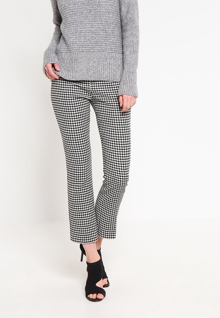 Gray knit sweater with a ribbed hem paired with black and white houndstooth patterned pants. Open-toe black heels complete the outfit.