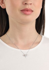 Silverfärgad trollslända-halsband med kristallaccenter, en delikat kedja, rund hänge med intrikata detaljer och en blank finish.