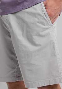 Light gray shorts made of smooth fabric, featuring side pockets and a simple design with neat stitching along the hem.