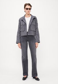 Grå cropped jakke med to frontlommer, kombinert med grå vide jeans og svarte leiligheter. Antrekket har en hvit topp under.