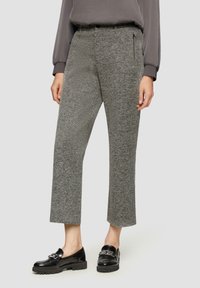 Spodnie w szary wzór houndstooth, o skróconej długości, z bocznymi kieszeniami na zamek. W zestawie z czarnymi lakierowanymi mokasynami. Tkanina ma teksturowany wygląd.