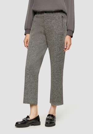 Pantalon à motif pied-de-poule gris, longueur raccourcie, avec poches zippées sur les côtés. Associé à des mocassins noirs en cuir verni. Le tissu a une apparence texturée.