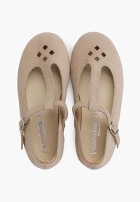 Zapatos Mary Jane de ante beige con detalles recortados, puntera redondeada, correa ajustable y plantilla acolchada. Suela plana para mayor comodidad.
