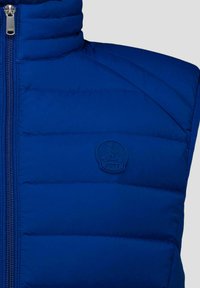 Blauer, gepolsterter ärmelloser Weste mit Reißverschluss vorne und geprägtem Logo einer Person auf einem Roller mit "JOTT"-Text auf der Brust.