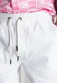 Shorts bianchi in cotone con vita elasticizzata, dotati di un cordoncino e punte nere a contrasto. Il tessuto presenta una leggera texture.