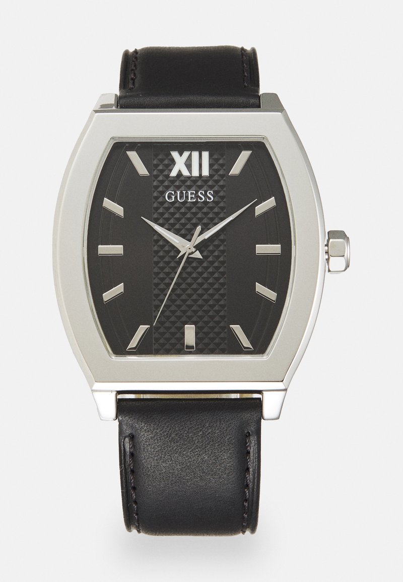 Schwarze rechteckige Uhr mit silbernen Metallakzenten, strukturiertem dunklen Zifferblatt, weißen Stundenmarkierungen und einem schwarzen Lederarmband. Markenlogo: Guess.