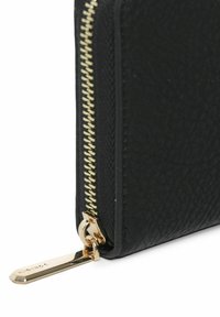 Portafoglio nero con texture, caratterizzato da una zip dorata con tirante e design elegante. Esterno liscio con dettagli di cucitura visibili.