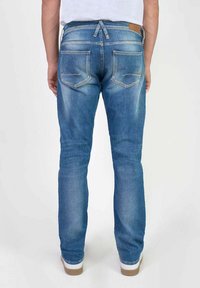 Vaqueros de denim azul claro con un ajuste slim, que cuentan con dos bolsillos traseros, una etiqueta de cuero marrón en la cintura y un detalle de cordón.