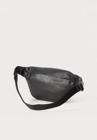 Bolso de cintura de cuero texturizado negro con correa ajustable y hebilla de plástico sobre un fondo neutro.