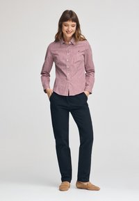 Rød og hvid ternet button-up skjorte med lange ærmer, parret med mørkeblå bukser og tan mokasinstil sko.