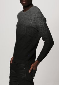 Maglione lavorato a maglia che passa dal grigio scuro al nero, con un motivo testurizzato, polsini a coste e un accento blu sull'orlo.