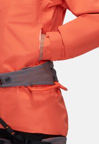 Orange vandtæt jakke med en lynlås lomme, tætsiddende manchetter og et gråt justerbart bælte med perforeringer og orange detaljer.