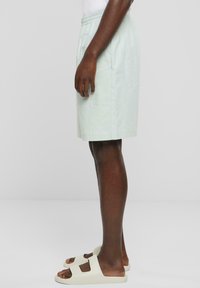Ljust gröna knälånga shorts med elastiskt midjeband och sidofickor. I kombination med off-white slidesandaler. Slät tygtextur.