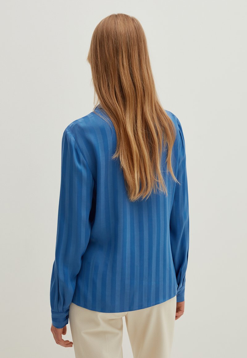 Langarmbluse in lebhaftem Blau, aus glattem Stoff mit vertikalen Streifen. Sie verfügt über knöpfbare Manschetten und ein lässiges Design.