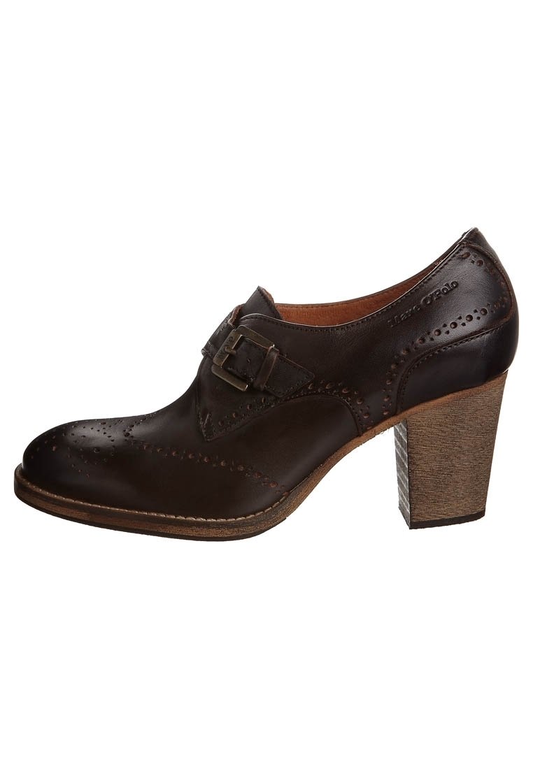 Hnědá kožená vysoce podpatková bota s brogue detaily, s akcentem na přezku a texturovaným dřevěným podpatkem. Hladký povrch a zaoblený design špičky.