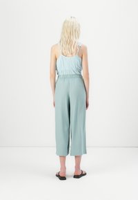 Haut sans manches bleu clair avec volants, associé à un pantalon court ample vert pâle. Tissus doux, design simple et taille élastique.