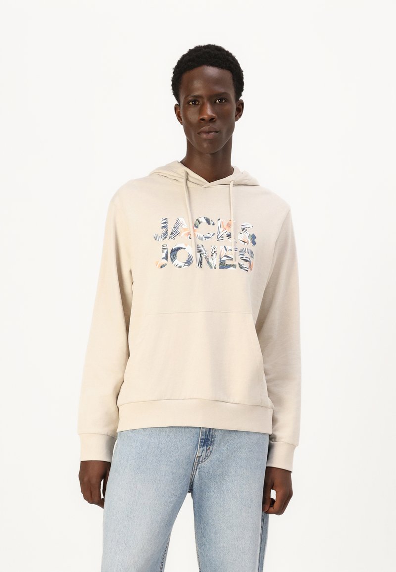 Sweatshirt à capuche beige avec une poche frontale, arborant un texte graphique floral multicolore "JACK & JONES". Tissu doux avec une coupe décontractée.
