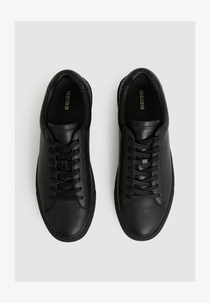 Fekete bőr sportcipők sima felülettel, kerek orral, hatlyukú fűzős kialakítással és alacsony profilú gumitalppal.