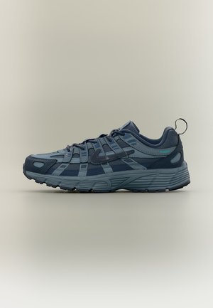 Baskets de sport bleues avec empiècements en mesh superposés et en synthétique, semelle épaisse texturée, fermeture à lacets à l'avant et boucle d’enfilage au talon, vue de côté.