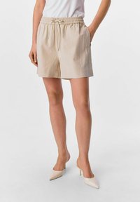 Pantaloni corti in misto lino beige con cintura elastica, cordino regolabile, tasche laterali e vestibilità comoda. Sfondo bianco.