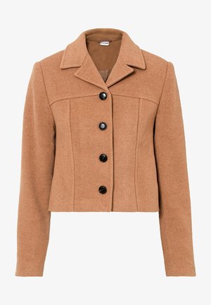 Frau geht, trägt eine camelfarbene kurze Jacke, schwarze Hose und schwarze Stiefeletten mit Absatz vor weißem Hintergrund.