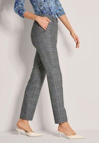 Grau karierte Hose mit taillierter Passform, flachem Bund und Seitentaschen, kombiniert mit einem blauen Paisleymuster-Oberteil und cremfarbenen Absatzmules.