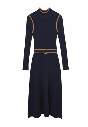 Marineblå ribstrikket kjole med lange ærmer, høj hals og en tætsiddende bodice. Har et kontrasterende brunt bælte og et skørt med vidde.