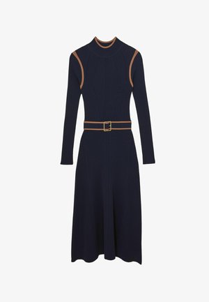 Marineblå ribstrikket kjole med lange ærmer, høj hals og en tætsiddende bodice. Har et kontrasterende brunt bælte og et skørt med vidde.