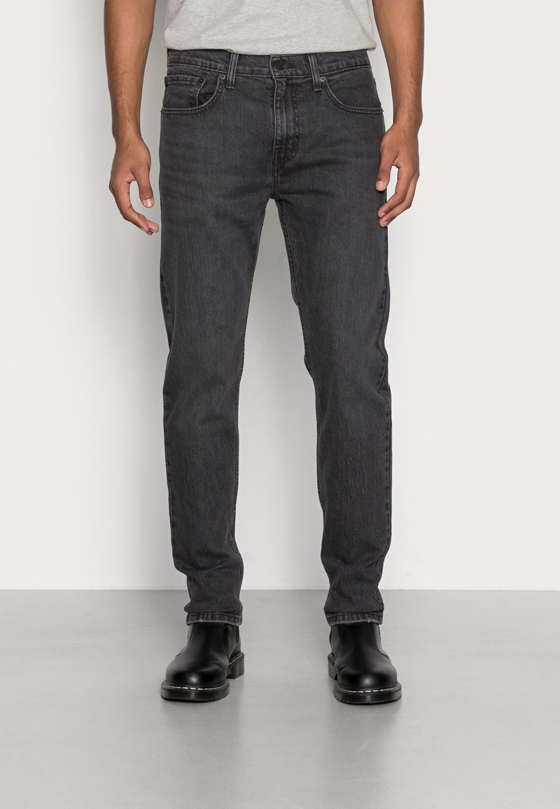 Zwarte denim jeans met een rechte pasvorm, vijf-pocket ontwerp en subtiele vervaging, gecombineerd met zwarte enkellaarsjes. Gladde textuur en geweven stof.