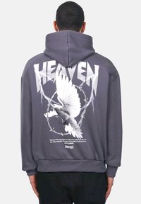 Grå hættetrøje med et stort hvidt duegrafik, teksten "HEAVEN" og en detalje med pigtråd på ryggen. Blødt materiale med en afslappet pasform.