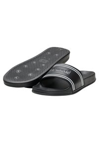 Sandales noires à glissière avec une semelle en caoutchouc texturé et une large sangle avec des rayures blanches. Le nom de la marque est en relief sur la sangle.