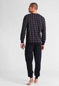 Marineblauw loungewear set met een lange mouwen top in een ruitpatroon en bijpassende broek met elastische manchetten en een ontspannen pasvorm.