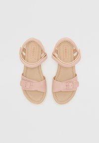 Sandales roses avec une tige synthétique lisse, sangle ajustable avec boucle, semelle intérieure rembourrée et semelle plate avec des détails de couture.