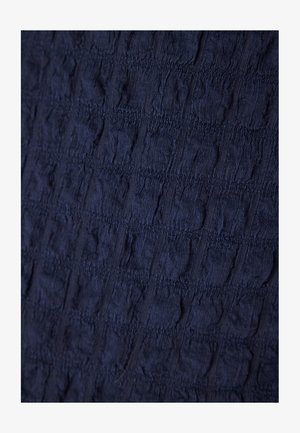Navy textured fabric with a crinkled pattern and ridges, featuring alternating raised and flat sections. Soft, lightweight material.