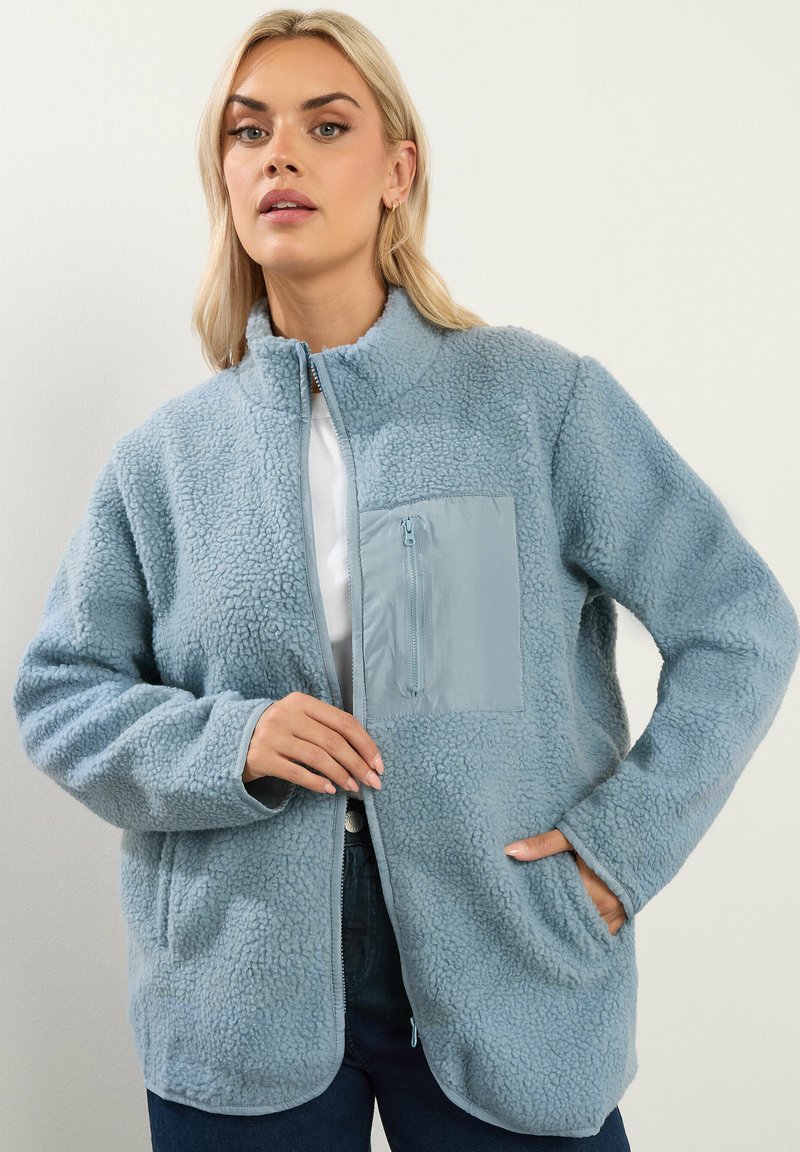 Giacca in pile blu cielo con colletto alto, superficie testurizzata e tasca frontale con zip in un materiale a contrasto. Maniche lunghe e tasche laterali.