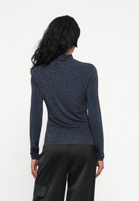 Langermet topp i mørk blå med leopardmønster, med en tettsittende design og myk stoff, kombinert med svarte cargo-bukser.