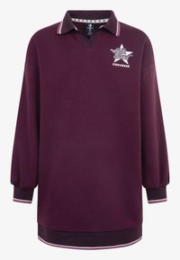 Polo majica dugih rukava u tamnocrvenoj boji s V-izrezom, kontrastnim ovratnikom, gumiranim logotipom i prugastim manžetama. Izrađena je od meke pamučne mješavine.