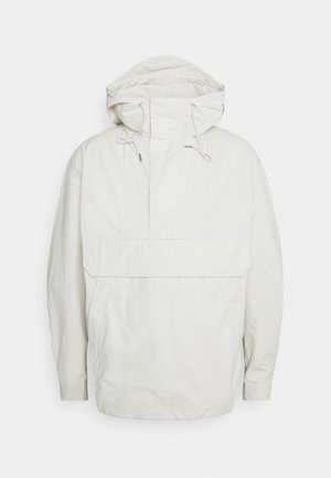 Anorak blanc léger avec capuche, poche frontale en forme de poche kangourou, fermetures à cordon de serrage, et coupe décontractée. Tissu lisse légèrement texturé.